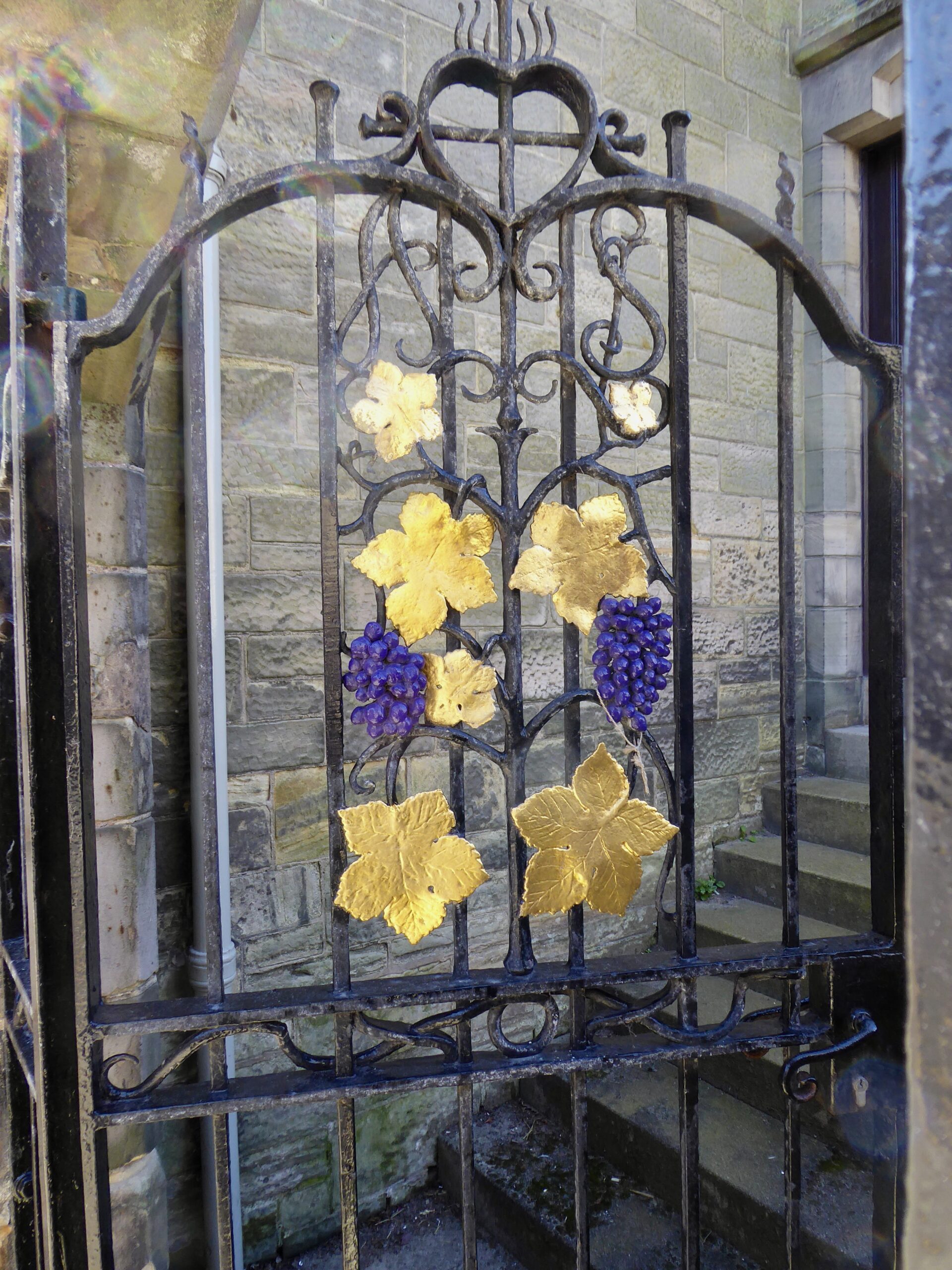 Ornamental wrought iron gate, ornamented with gilt leaves and purple grapes