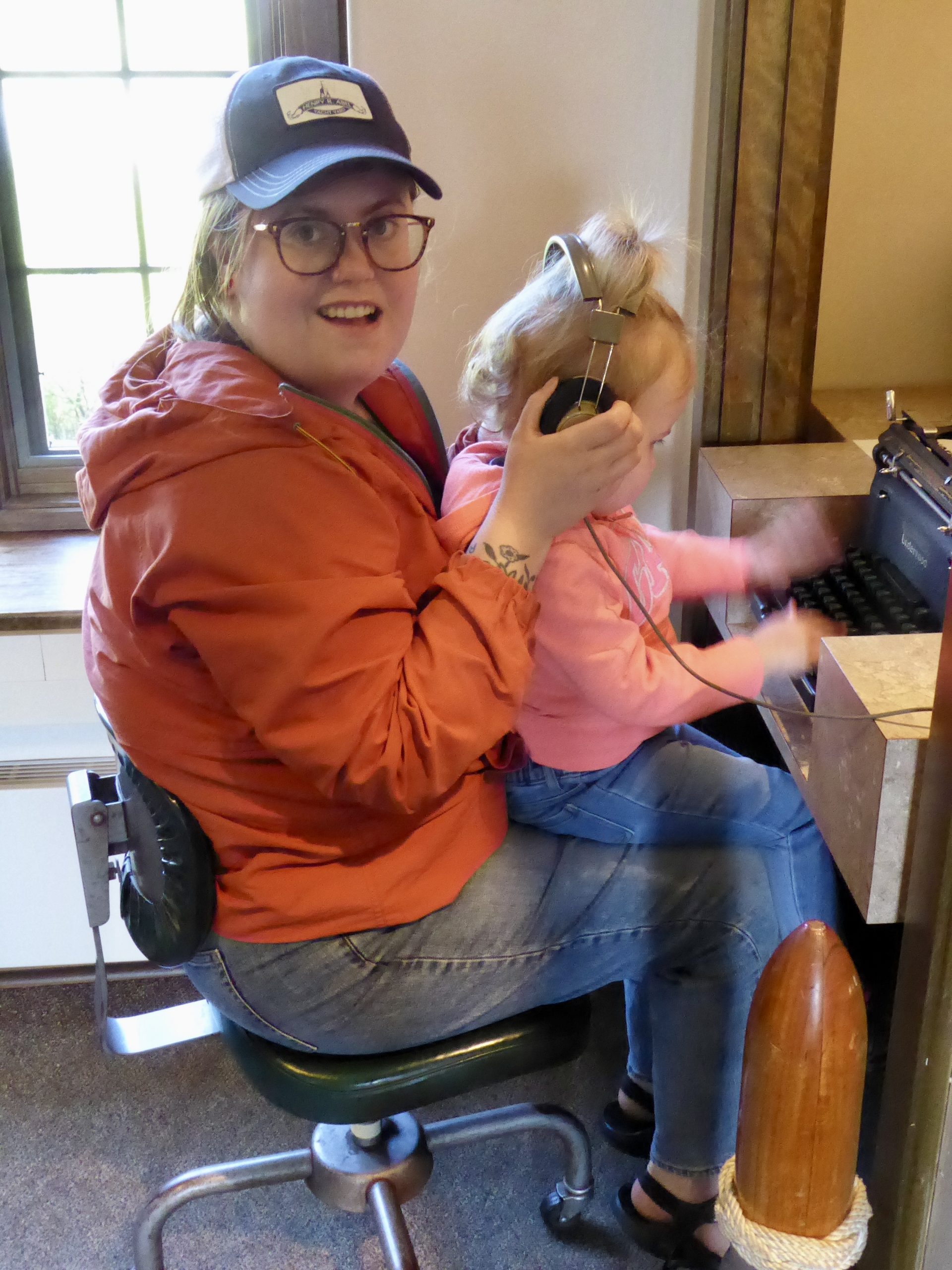 Woman (Pippa) with girl on her lap, which girl is encountering a typewriter keyboard with fascination
